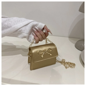 Detailed view of mini gold crossbody bag featuring metal bow and delicate chain strap