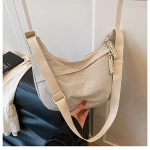 Détail du sac bandoulière croissant beige en nylon avec tirette à nœud tissé