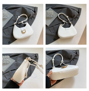 Detail view showing white crescent suede bag with golden D-ring buckle and knotted handle