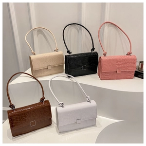 Detail view of five croc-embossed shoulder bags in various colors on white stairs