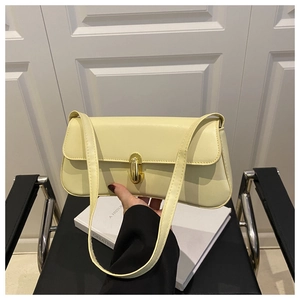 Close-up of minimalist cream leather underarm bag with gold oval twist lock and sleek strap