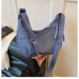 Détail du sac dumpling en nylon bleu avec large sangle tissée et boucle réglable