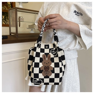 Detail of checkered knitted bucket bag with 3D cute rabbit and houndstooth handle