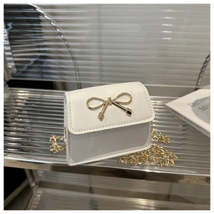Detailed view of white mini crossbody bag with golden bow buckle and chain strap
