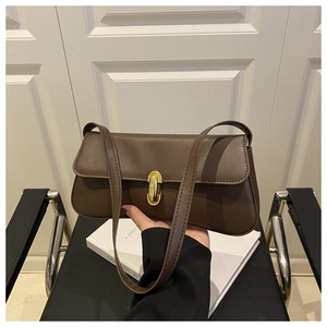 Detail of coffee brown baguette bag showing matte faux leather and gold oval twist lock