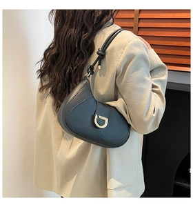 Detail of black leather half-moon bag with gold D-buckle and knotted shoulder strap