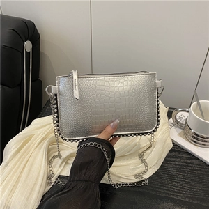Borsa a catena argento texture coccodrillo con perline su tavolo di legno nero