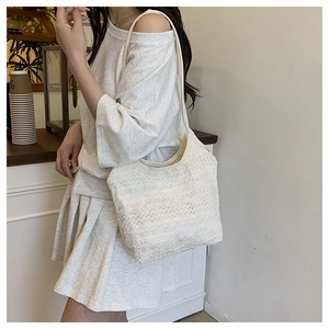 Gros plan sur le tissage de dentelle ivoire et la texture crochetée de ce sac