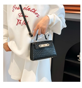 Detail of black woven texture handbag with gold metal twist lock and shoulder strap