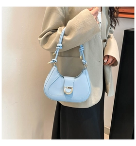 Detail of light blue leather underarm bag with knot strap and gold D-ring buckle