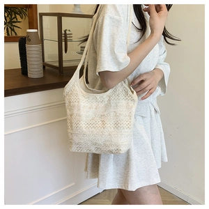 Gros plan sur un sac cabas en dentelle blanche aux motifs floraux ajourés complexes