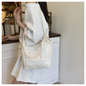 Detail of white hollow lace crochet tote bag with intricate woven floral patterns
