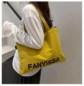 Close-up of a large yellow nylon tote bag with textured fabric and woven brand label