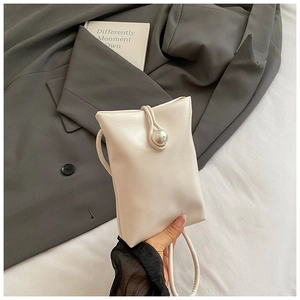 Detailed view of cream mini crossbody bag featuring a large pearl clasp and PU leather