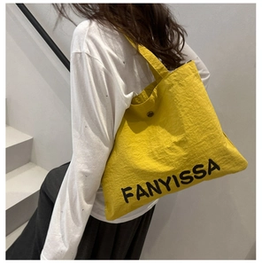 Detail of a bright yellow tote bag showing FANYISSA print and metal buckle closure