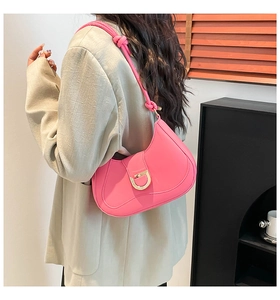 Detail of pink glossy leather hobo bag with gold metal buckle shown on a shoulder