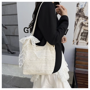 Gros plan sur le sac à bandoulière en dentelle blanc crème avec un nœud floral sur la sangle