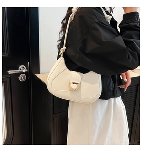 Close-up of a white hobo bag with gold metal hardware and a stylish knotted shoulder strap