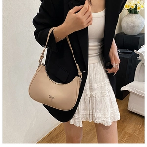 Detail of apricot crescent hobo bag with a delicate metal bow accent and leather strap