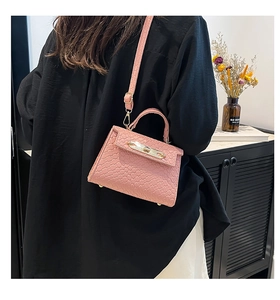 Detail of pink woven leather mini bag with gold hardware worn on a black outfit