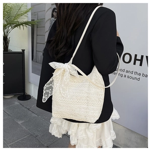 Detailed view of cream lace fabric texture and bow accent on a summer shoulder bag