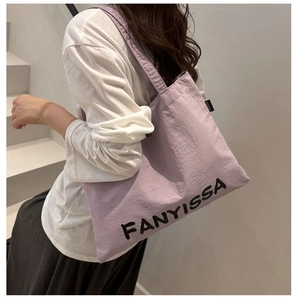 Detail of the FANYISSA lettering on a lilac purple nylon tote bag with a woven brand tag