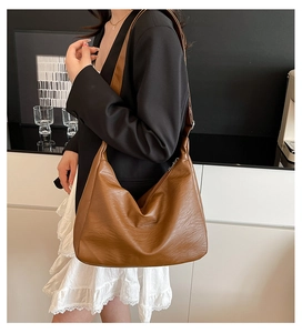 Detail of dark brown tote bag showing smooth leather texture and wide shoulder strap fit