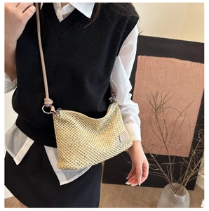Detailed close-up of beige woven straw bag featuring slim leather strap and knot detail