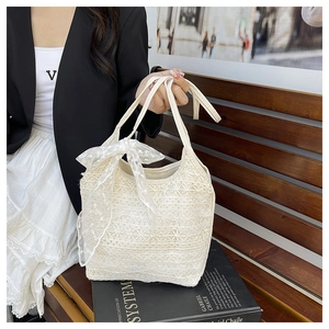 Close-up of beige lace tote bag featuring intricate floral patterns and a sweet bow detail
