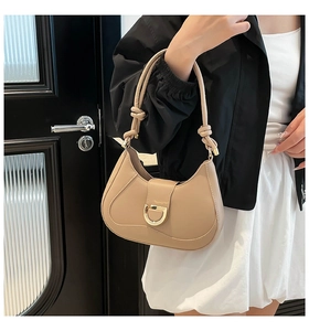 Detailed view of beige leather hobo bag featuring a gold D-buckle and knotted shoulder strap