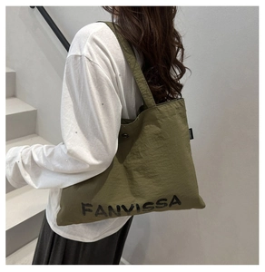 Detail of army green nylon tote bag with black letter print and texture on model