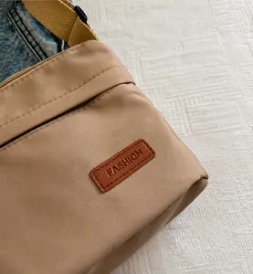 Vue détaillée du tissu en nylon kaki résistant et de l'écusson de mode en cuir du sac
