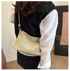 Detail of woven straw shoulder bag featuring leather trim and metal ring hardware