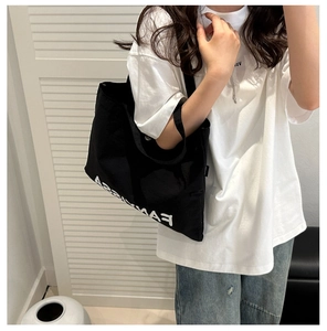 Detail of black canvas tote bag with FANNISSA print shown on model in casual style