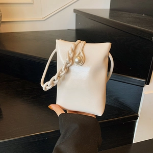 Elegant cream mini crossbody bag with large pearl clasp and textured shoulder strap