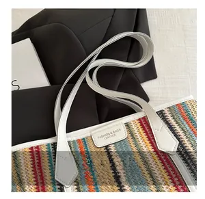 Détail du sac cabas tissé coloré avec poignées en cuir blanc et plaque de logo