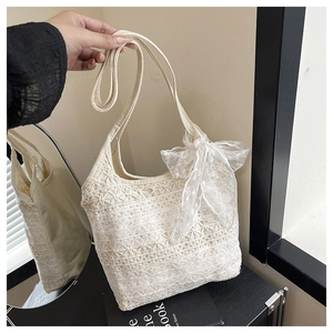 Gros plan détaillé du sac cabas en dentelle blanche avec nœud élégant et bandoulière