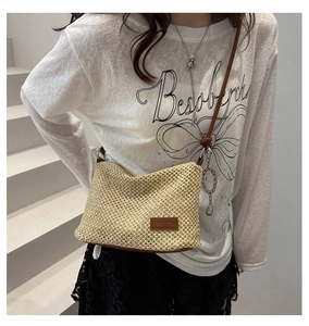 Detailed macro view of the beige woven texture and brown leather label on the crossbody bag