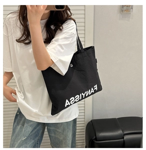Detail view of large black canvas tote bag with white text logo for student commuting