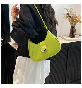 Detail view of neon green saddle baguette bag with gold D-buckle and knot strap detail