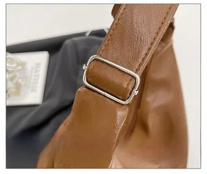 Close-up of silver metal buckle and strap stitching on a brown leather tote bag