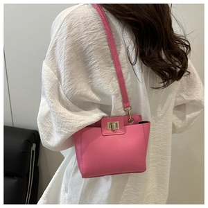 Détail de sac rose en cuir grainé avec un fermoir rotatif en métal doré élégant
