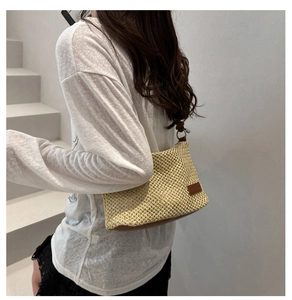 Detail of hand-woven straw shoulder bag featuring brown leather trim and metal ring buckle