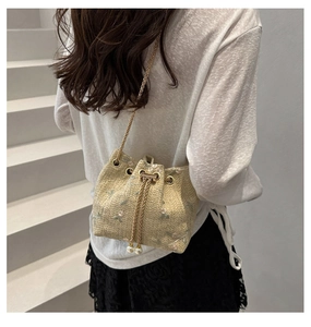Detail of woven bucket bag with floral embroidery and elegant pearl drawstring charms