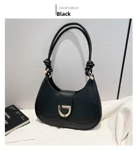 Detail of black leather crescent bag with golden D-buckle and unique shoulder knot