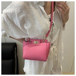 Gros plan du sac bandoulière rose en cuir grainé avec fermoir tournant doré élégant