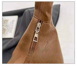 Detail shot of smooth silver metal zipper and brown litchi pattern leather bag