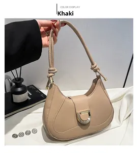 Detail of khaki leather baguette bag with gold horseshoe buckle and knotted handle