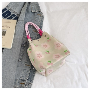 Detail of canvas bucket bag featuring pink floral cherry print and pink rope handle