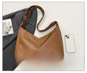 Close-up of brown PU leather hobo bag with wide strap, styled with blazer and magazine